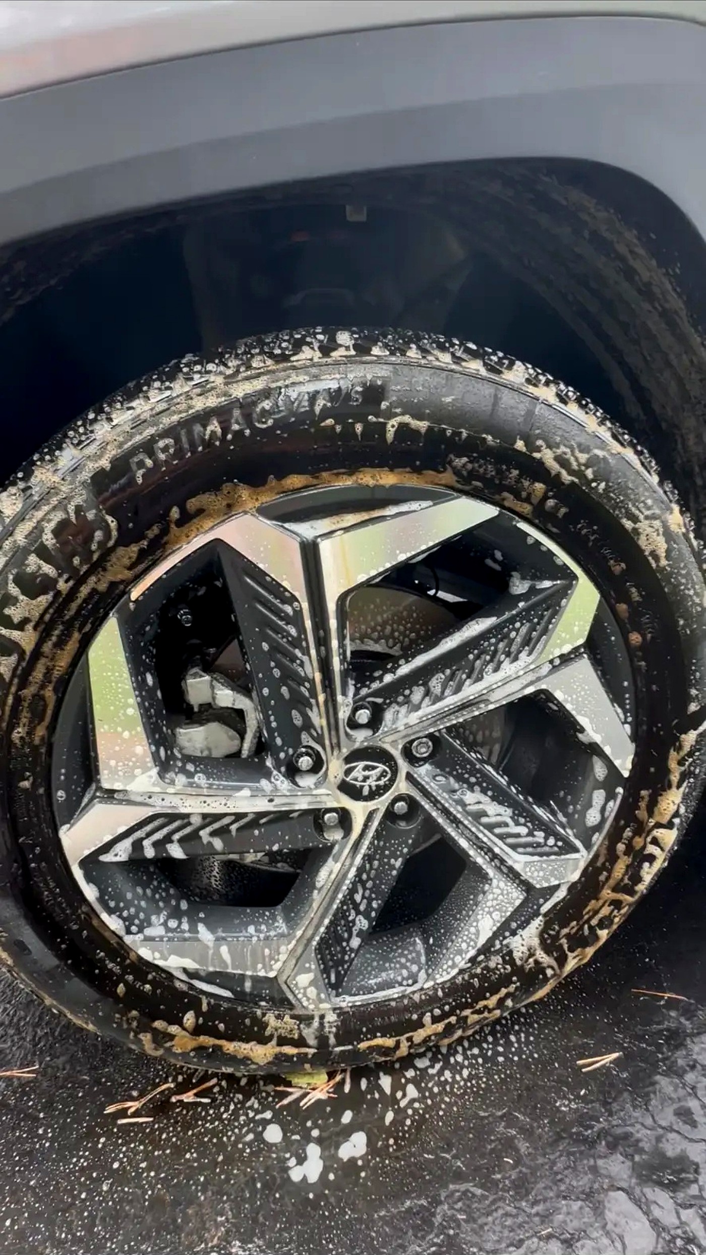 Wheel being scrubbed with soapy suds during a mobile wash
