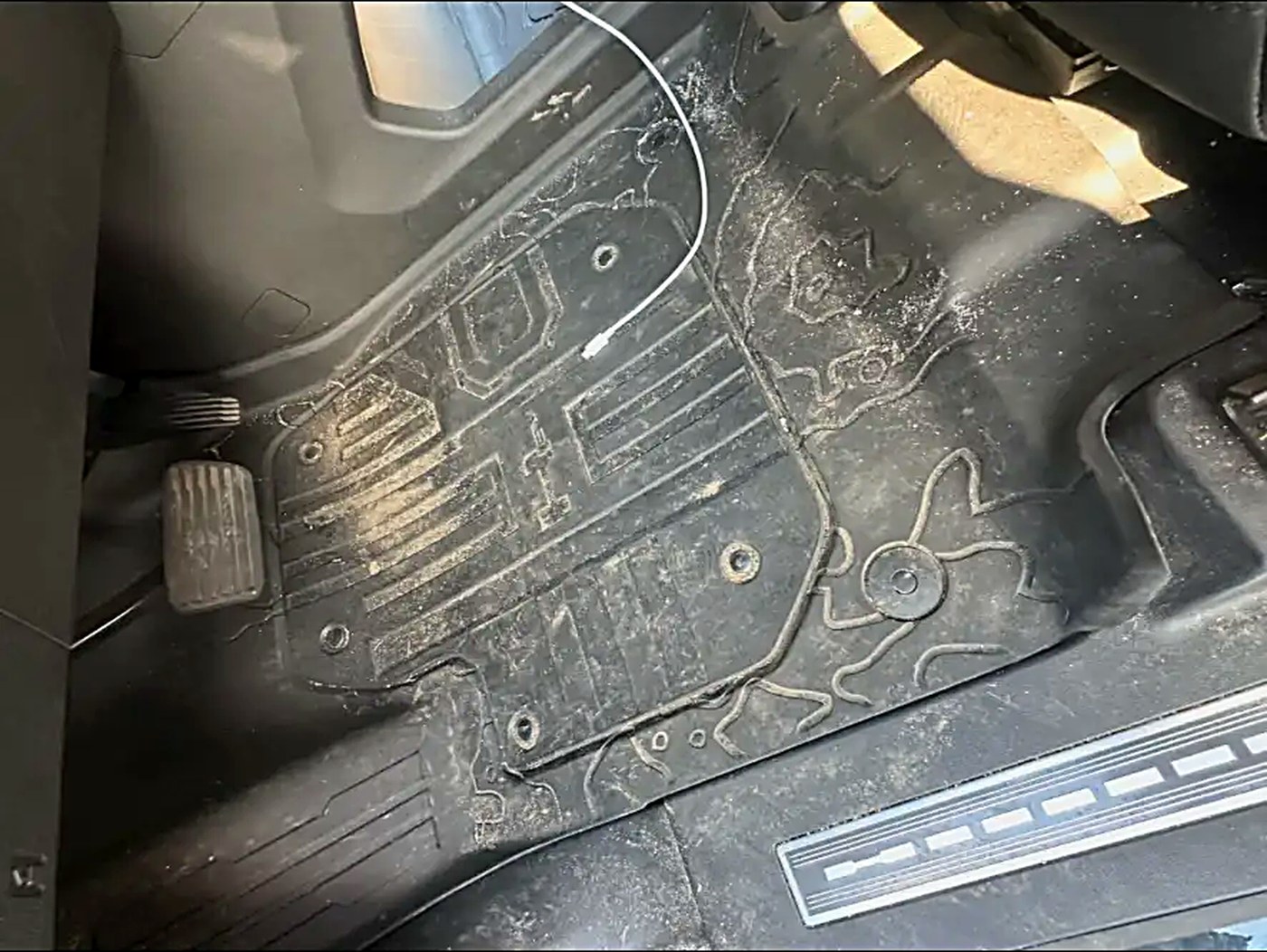 Heavy dirt and sand built up in a truck floor mat before cleaning