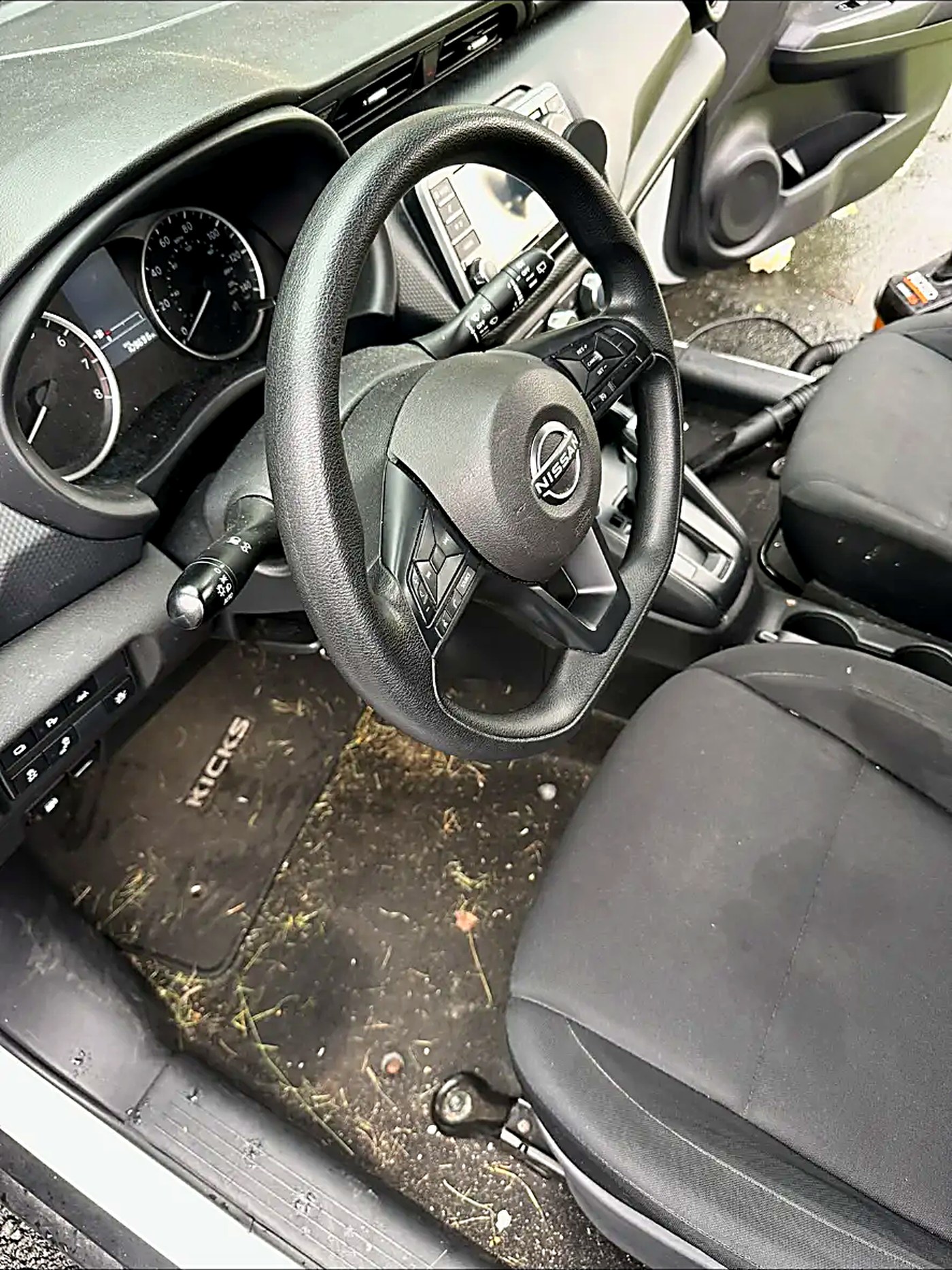 Nissan Kicks driver footwell full of grass and debris before cleaning